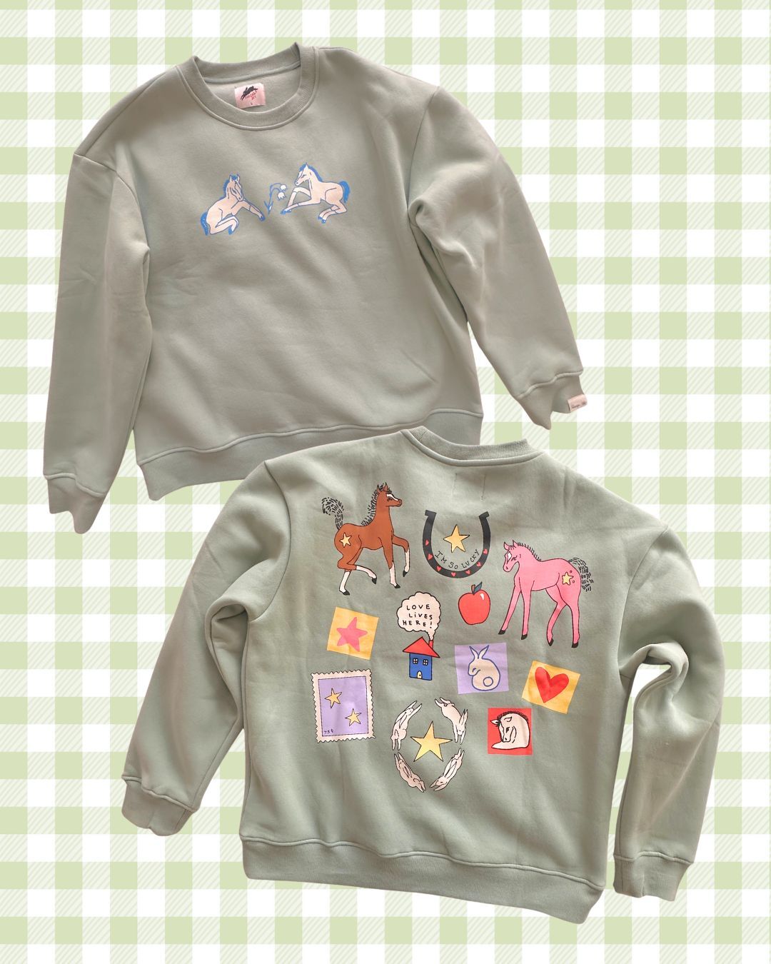 Two gray sweatshirts with colorful graphics on a green checkered background