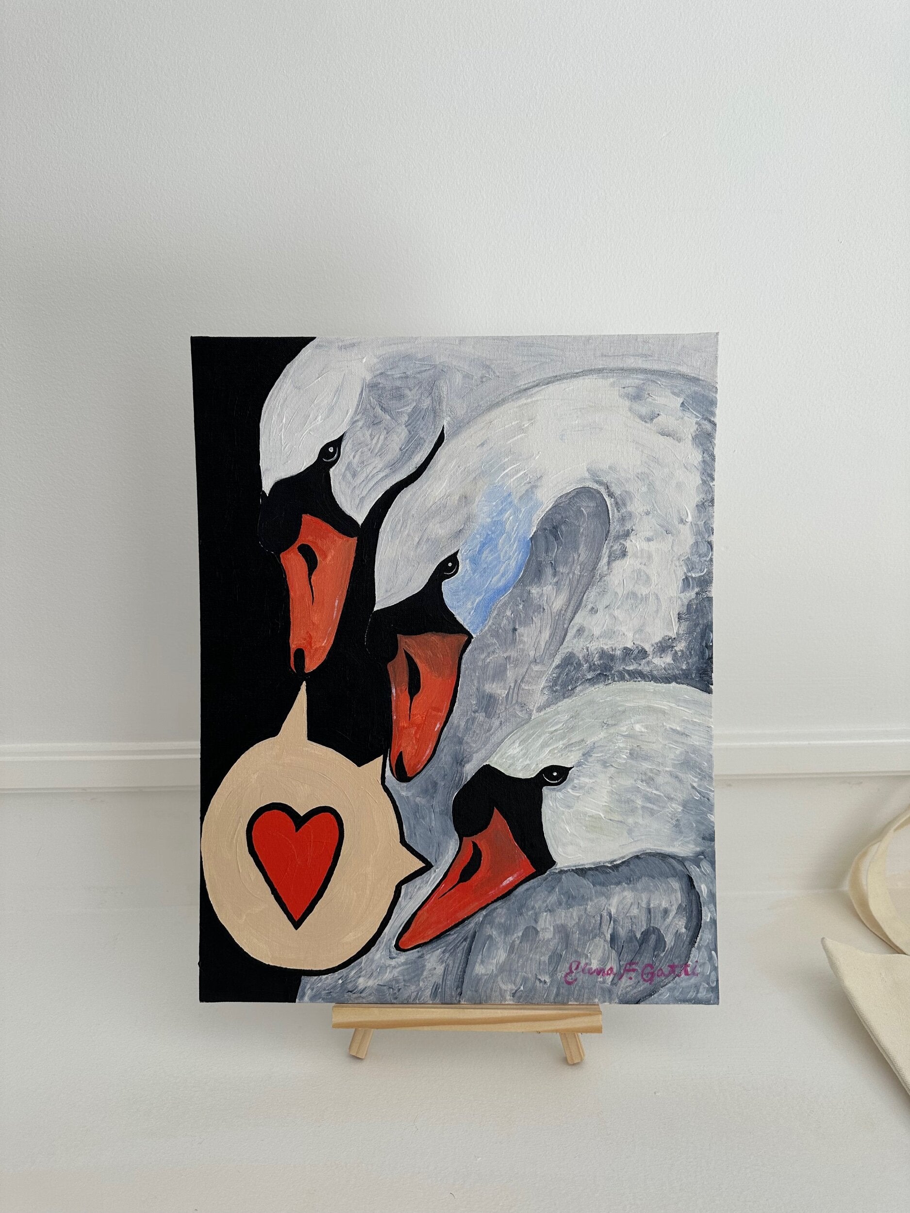 a trio of swans with a speech bubble that contains a heart