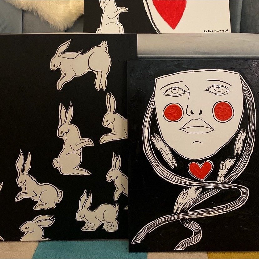 two canvases are pictured. one is image of a mask with ribbons coming off the sides. Bunnies are depicted running on the ribbons. the other canvas depicts a group of bunnies in various poses.